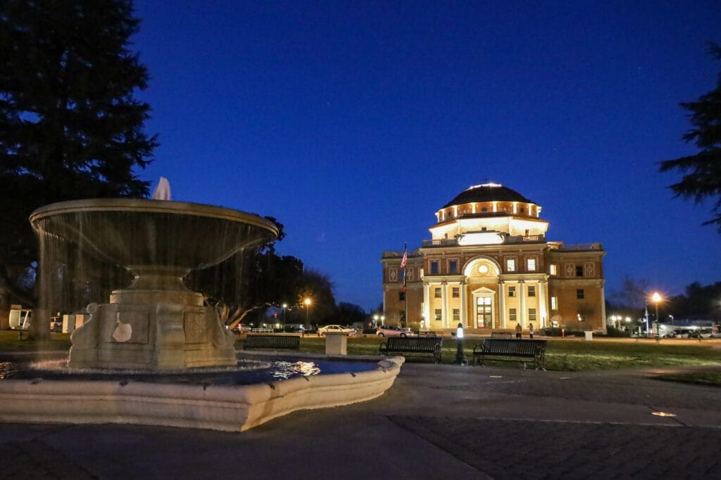 A fountain in front of a large building at night in Atascadero.