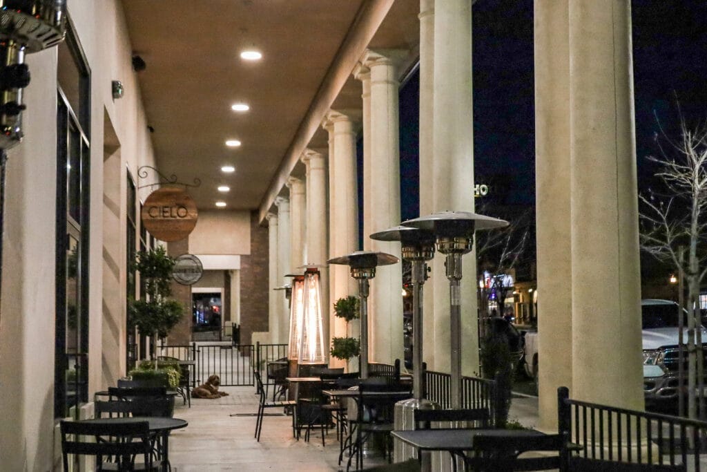 A sidewalk with tables and chairs at night in Pismo Beach.