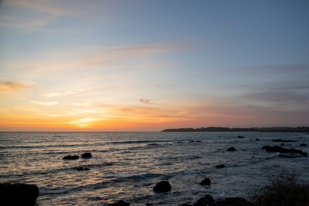 A sunset over the ocean with rocks in the background at Pismo Beach.