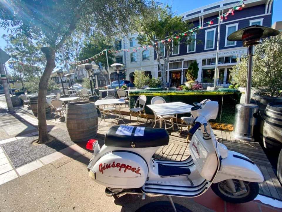 A vespa parked in front of a restaurant in Pismo Beach.