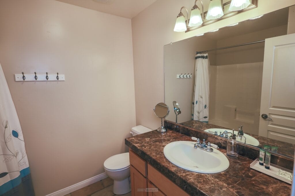 A vacation rental in Paso Robles on the central coast with a bathroom featuring a toilet, sink, and mirror.