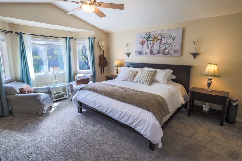A bedroom with a bed, chair and a ceiling fan in Pismo Beach.