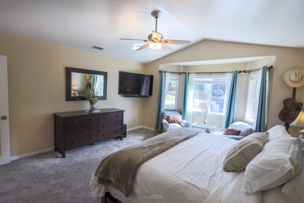 A vacation rental in Morro Bay with a bedroom featuring a bed, dresser, and ceiling fan.