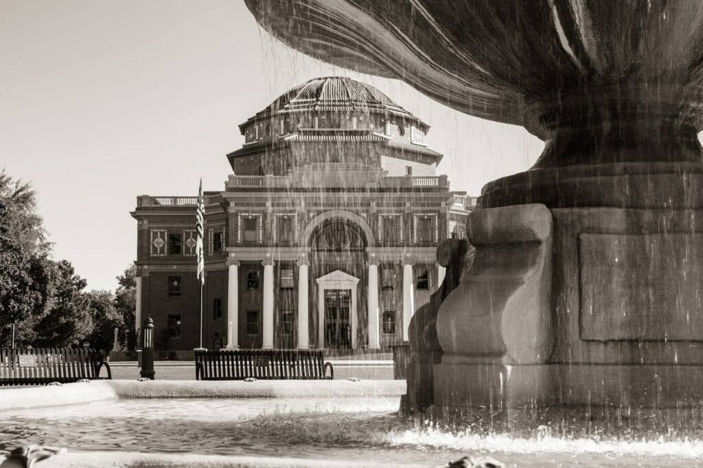 A black and white photo of a fountain in front of a building in Paso Robles.