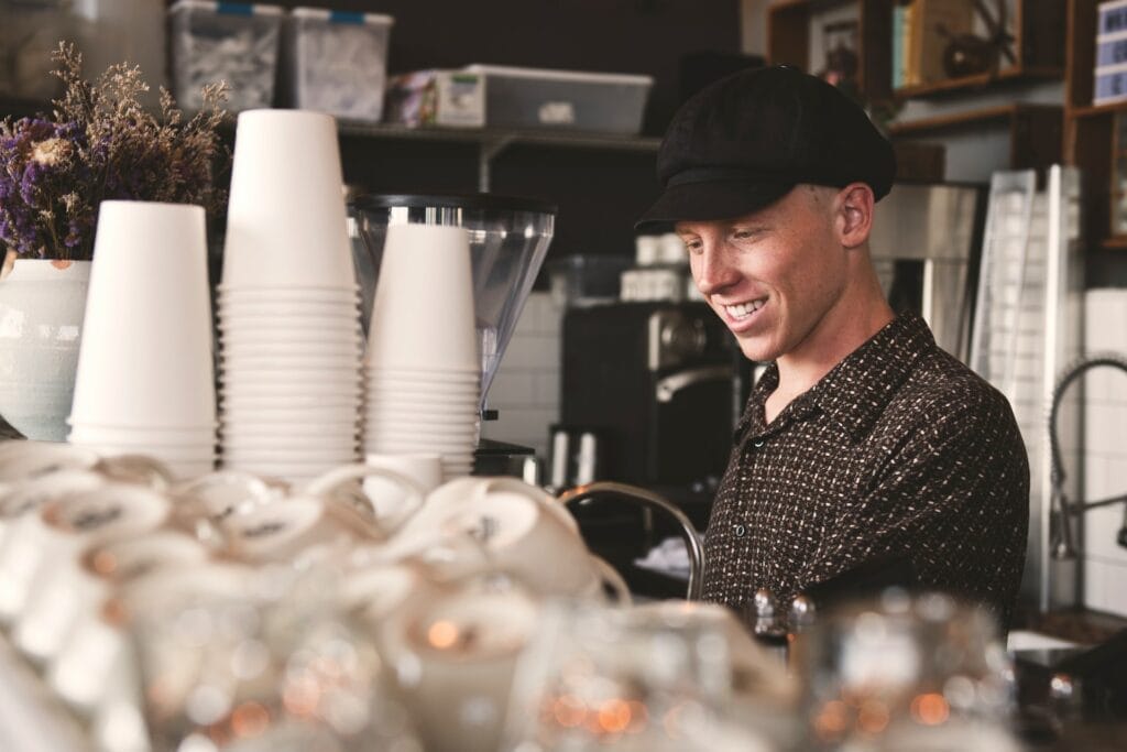 A man smiling at the counter of a coffee shop in Pismo Beach.