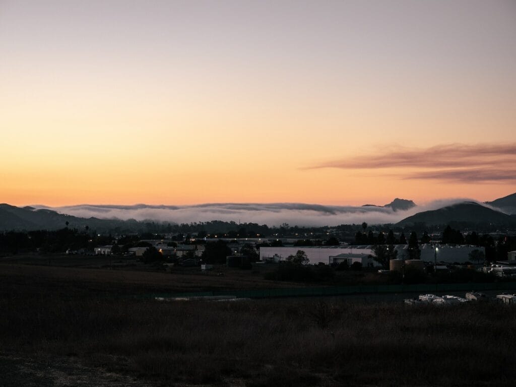 A sunset over a field with mountains in the background on the central coast.