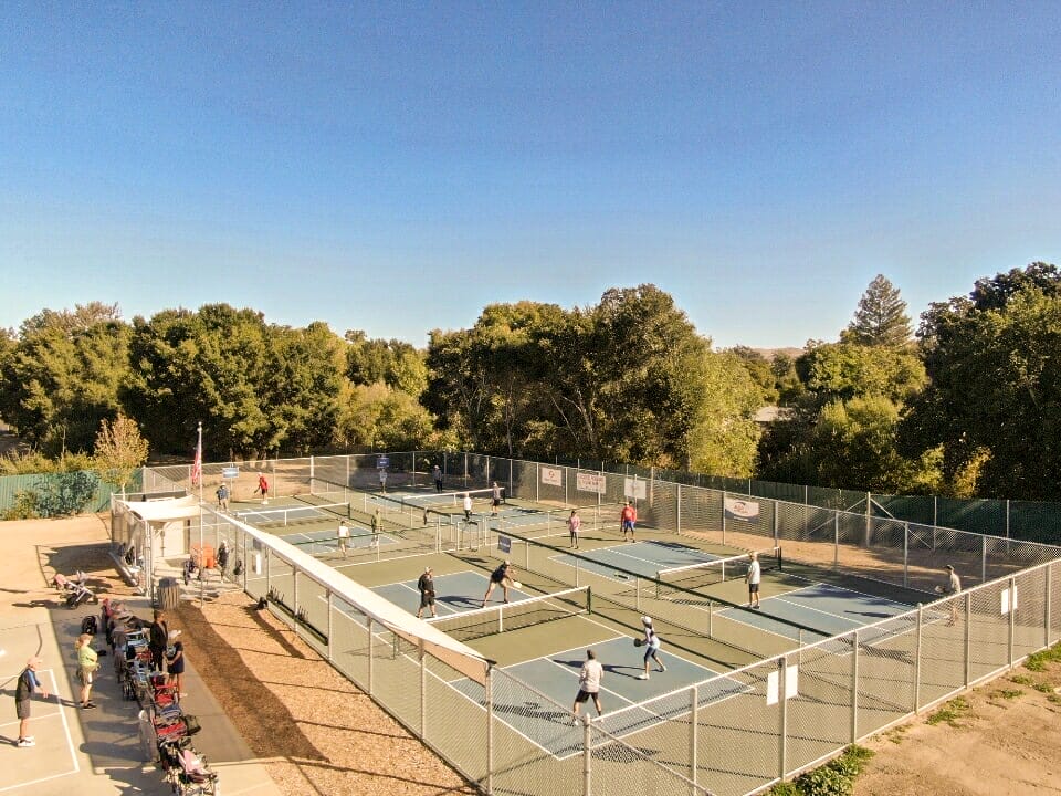 A group of people enjoying a game of tennis on a tennis court in Pismo Beach.